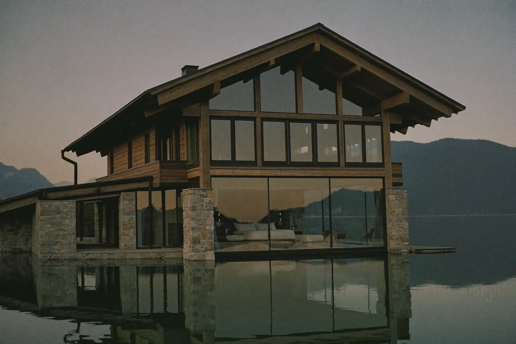 Ein Haus aus Holz und Stein am Ufer eines Alpensees.
