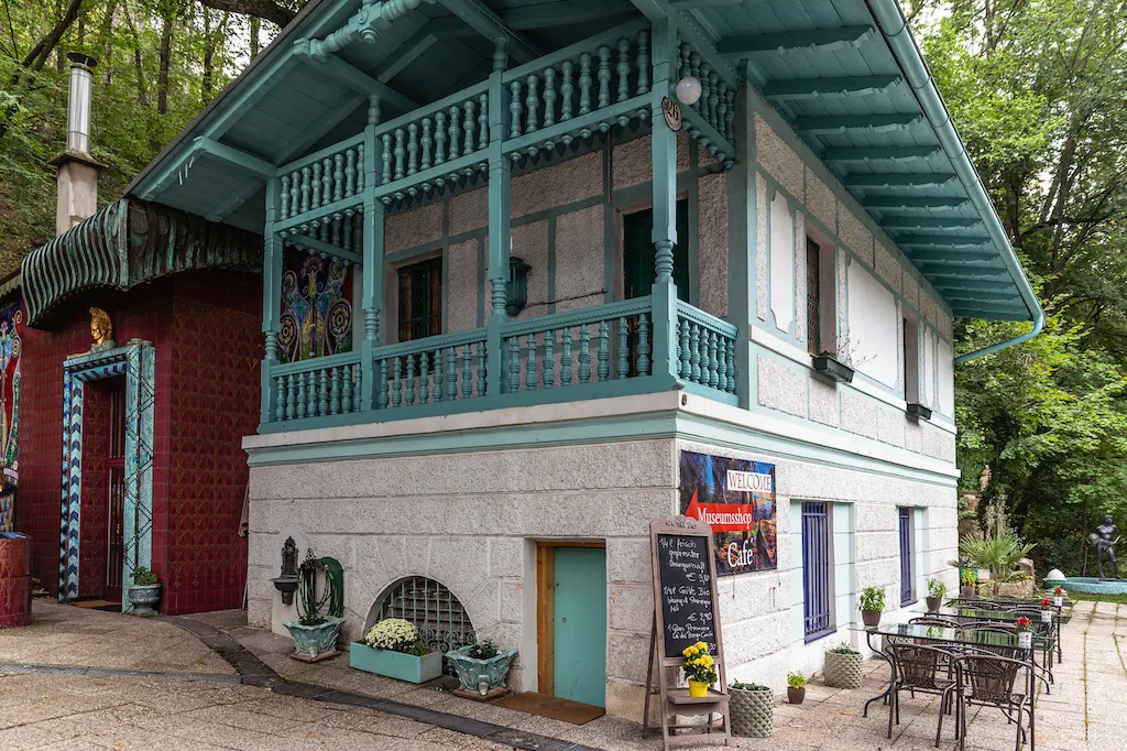 Das Galerie Café Esther: das ehemalige Pförtnerhaus mit türkisem Holzbalkon im Garten der Villa.