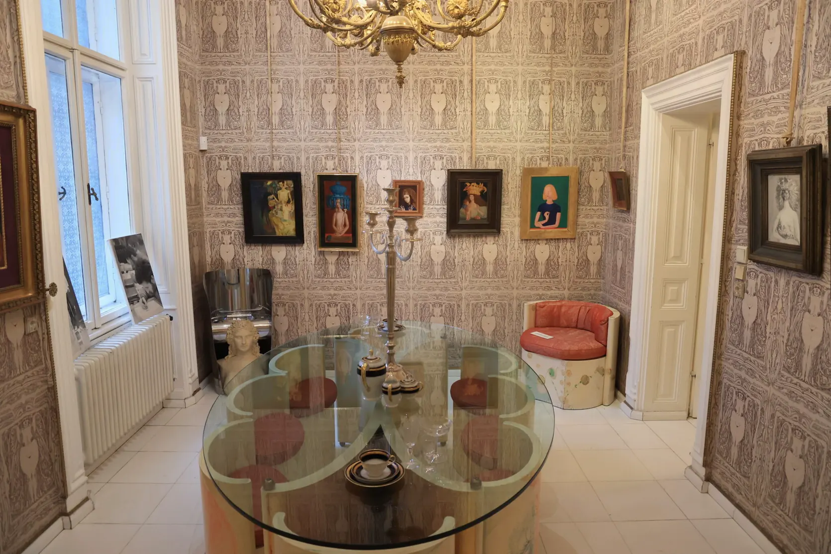 Ein kleiner Salon der Villa mit Glastisch, zwei Sesseln und gemusterten Wänden.