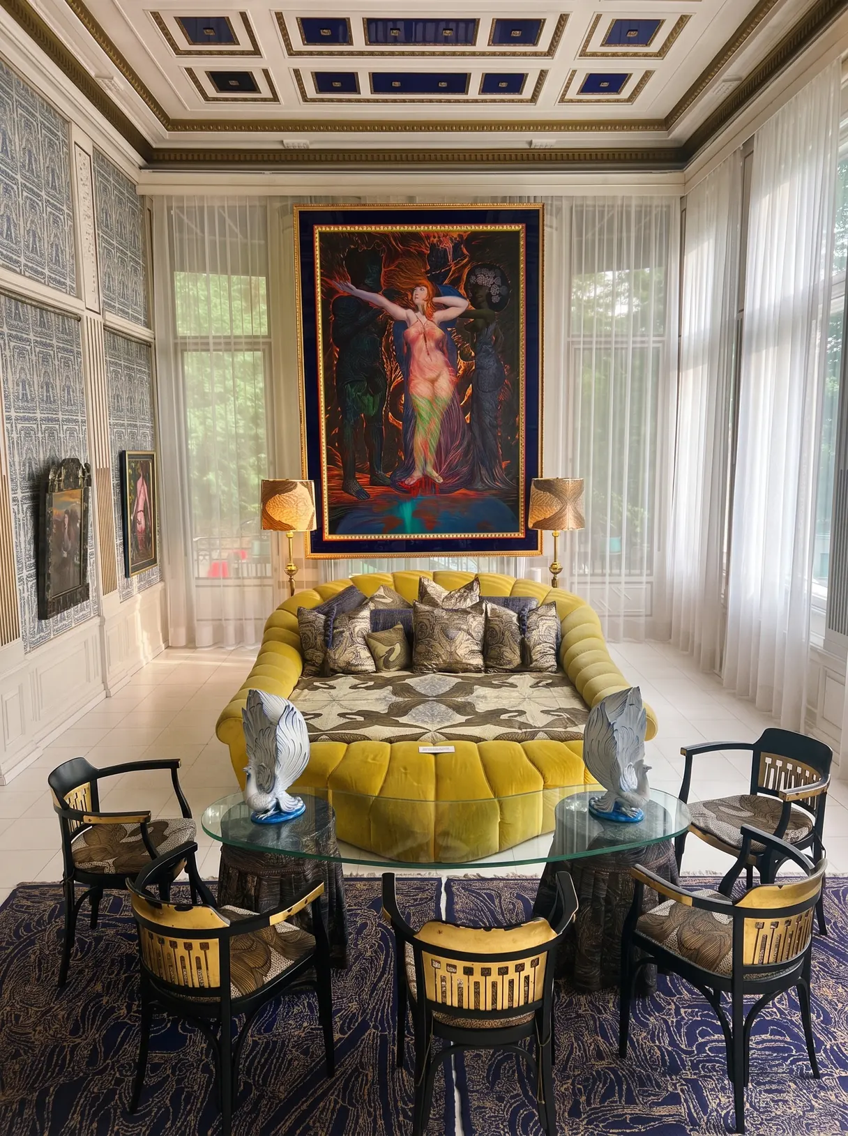 Salon der Villa mit rundem gelbem Sofa, Jugendstil-Stühlen und einem großformatigen Gemälde.